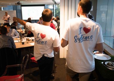 Two attendees wearing 'I Love Systems' branded white t-shirts at a systemHUB business workshop event